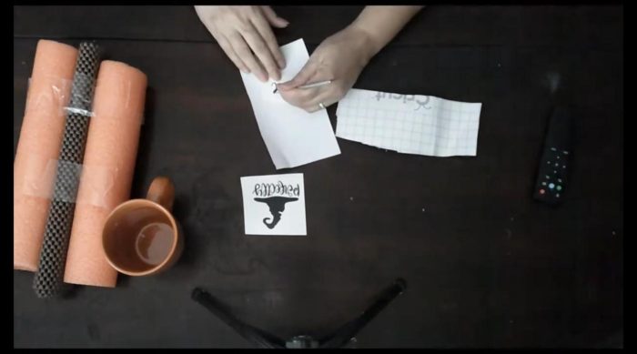 Weeding a black Perfectly Wicked witch hat vinyl decal for a dollar store Halloween mug